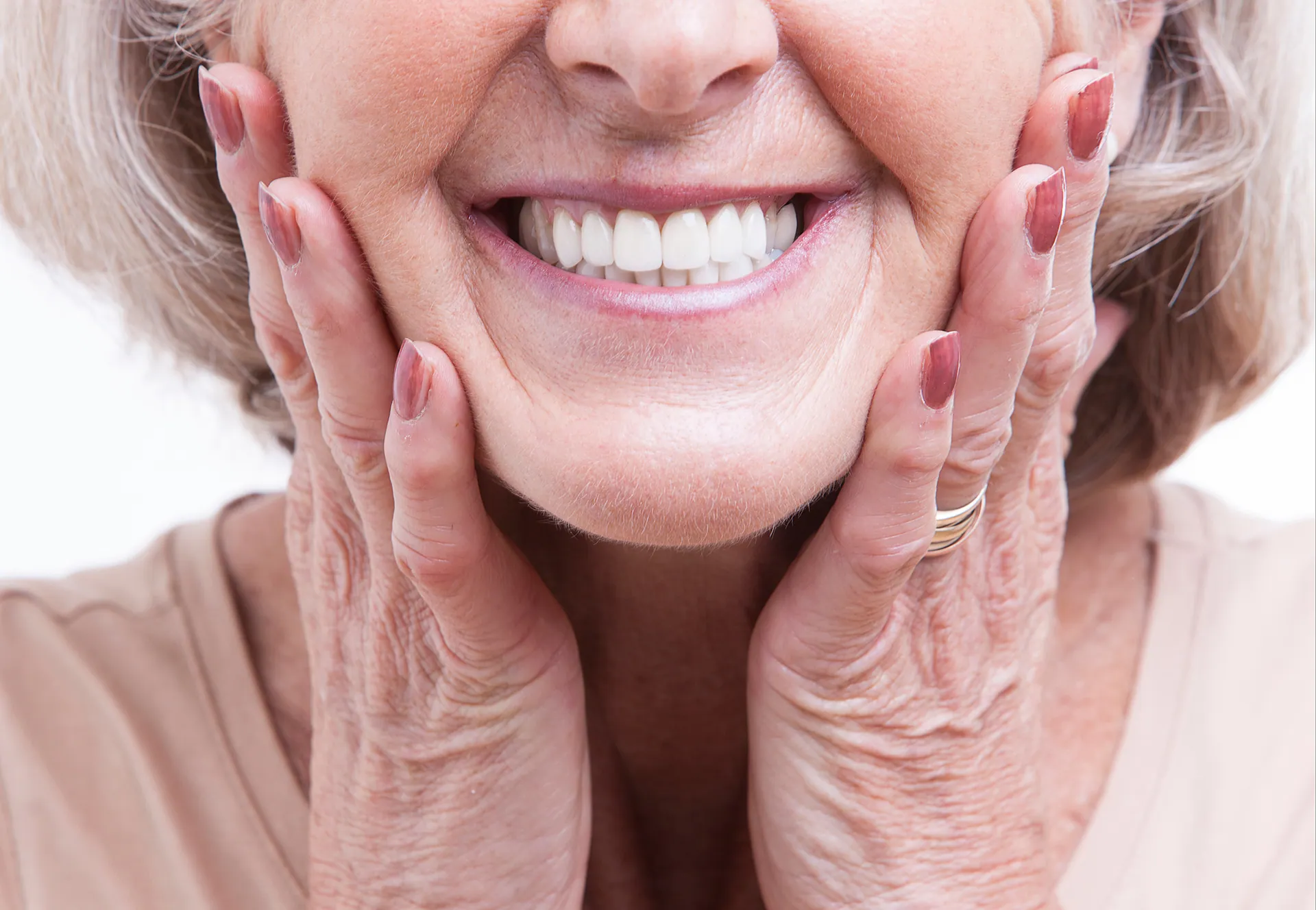 A happy woman with a beautiful, bright smile framing her face with her hands, showcasing dental veneers