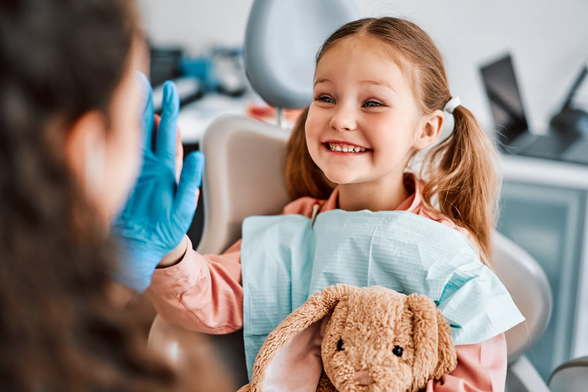 A happy child high-fiving her dentist during a comfortable dental visit
